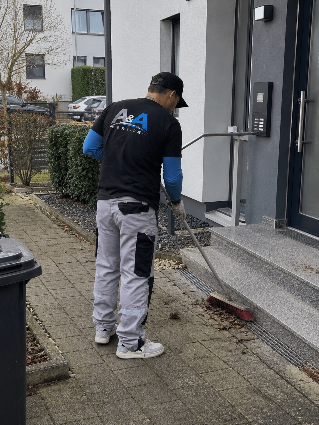 A&A Service Mitarbeiter kehrt den Eingangsbereich eines Wohnhauses